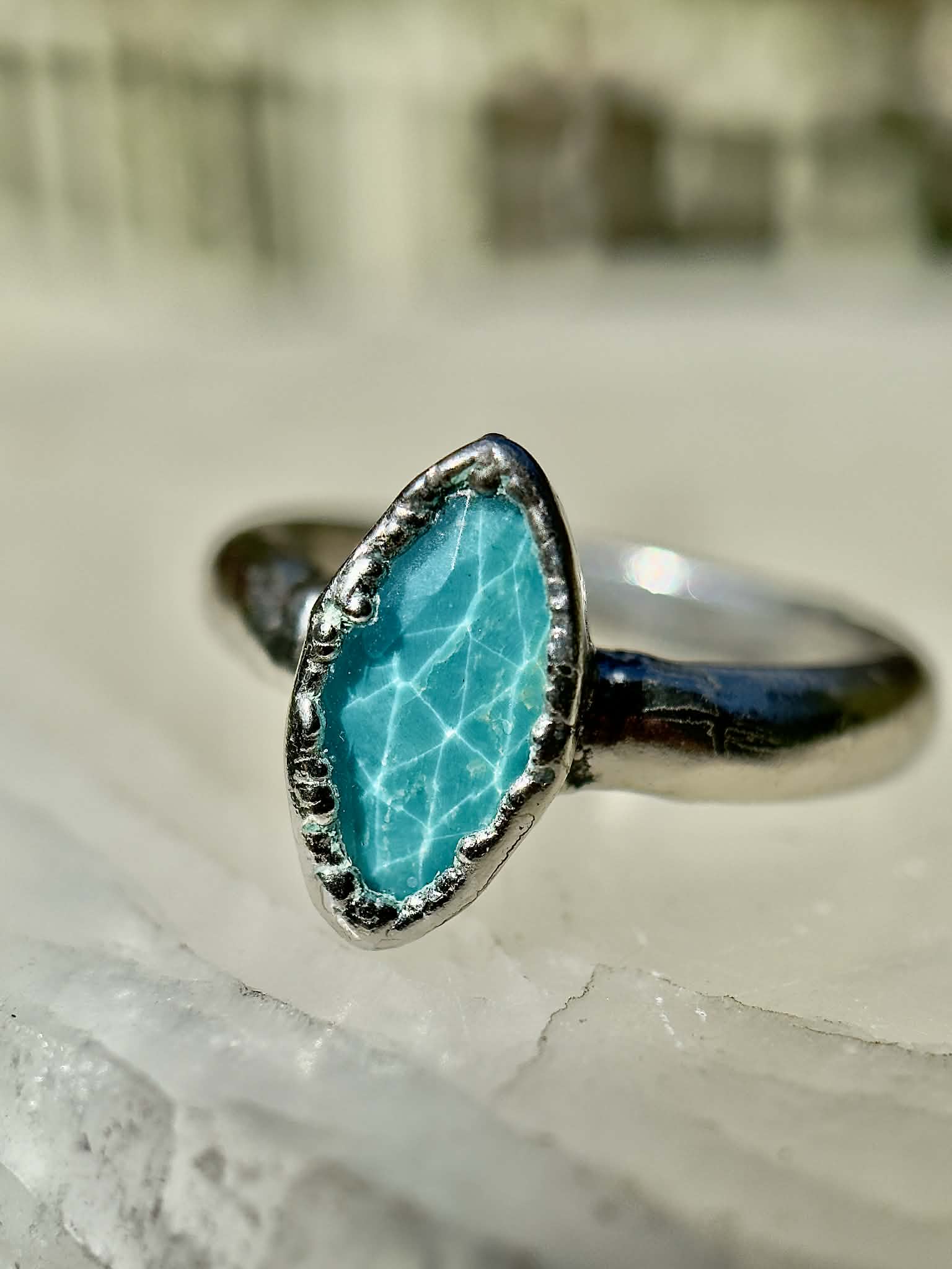 Silver ring with a turquoise stone on a textured surface
