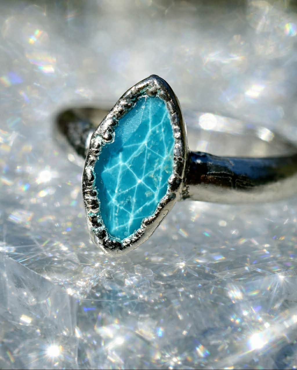 Turquoise stone ring with silver band on a glittery background